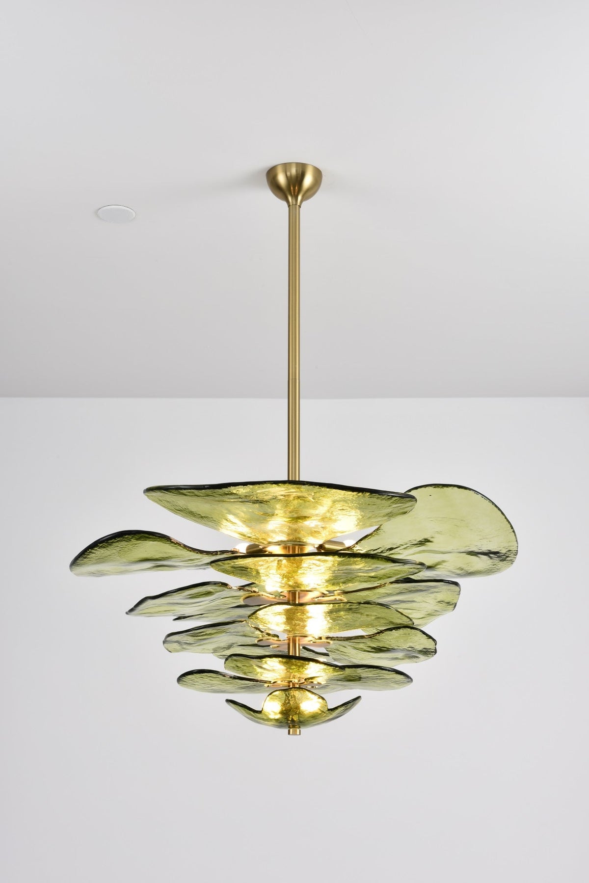 Green and gold Clérachic chandelier on a grey backdrop, its olive petals stacked in tiers with brass spacers between them.