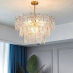 Lit Clérachic glass-shade pendant hanging from a white ceiling beside deep blue curtains and a large green leaf.