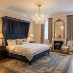 Layered clear-glass Clérachic pendant glowing above a navy upholstered bed in a classic bedroom with a patterned rug.