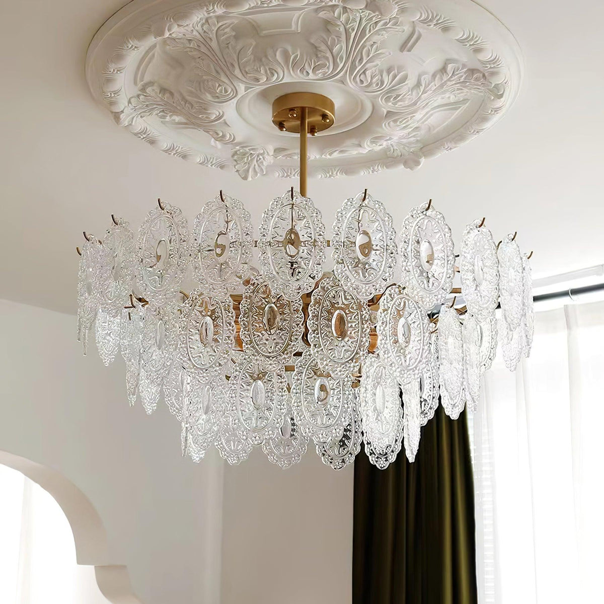 Looking up at the clear, patterned glass panels of this Clérachic pendant, beneath a carved ceiling rose and a dark green curtain.