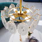 Close view of the gold ring, four candle-style bulbs and wavy wire arms holding the glass panels on this Clérachic pendant.