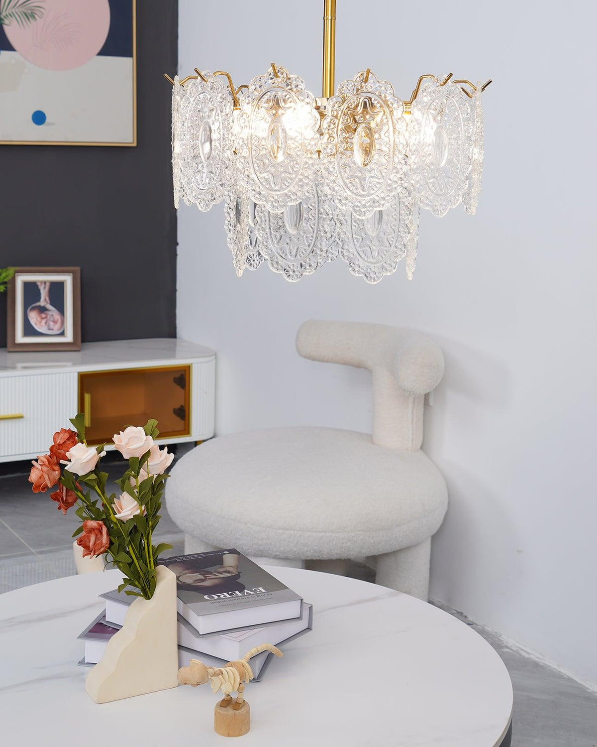 Side view of a Clérachic glass pendant beside a white boucle chair and a framed picture, against a light grey wall.