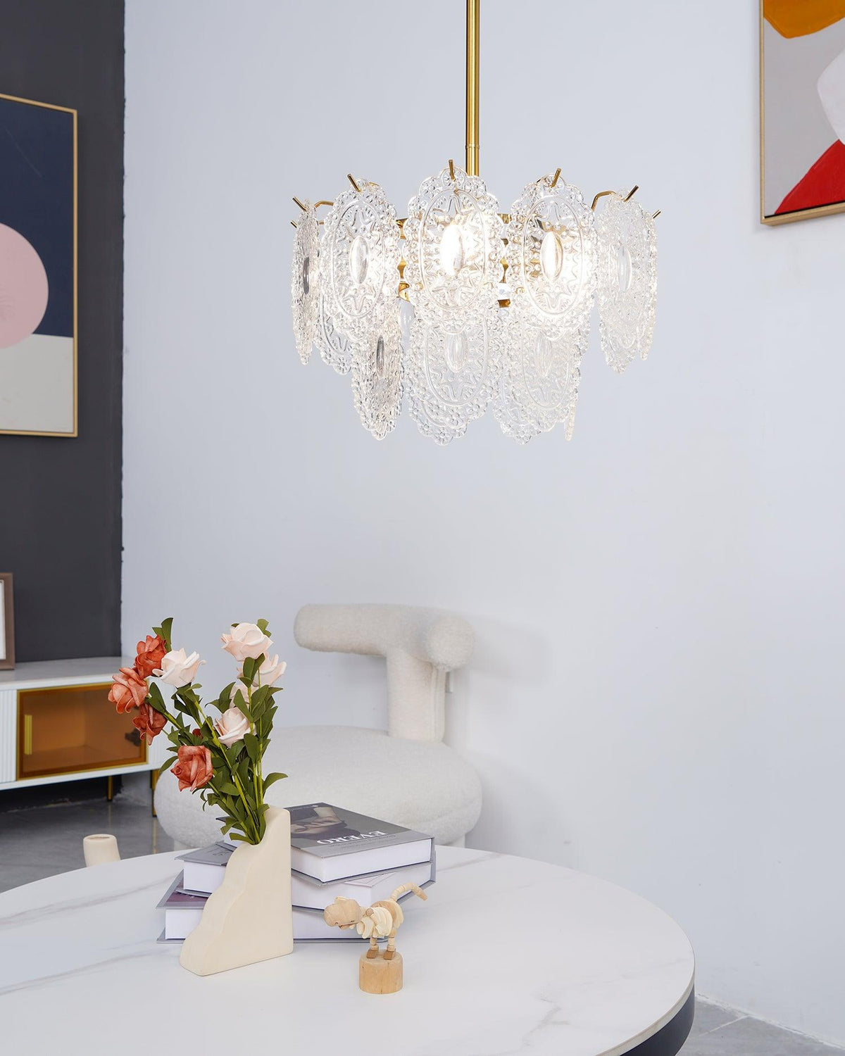 Compact Clérachic glass pendant lit above a white marble table and a vase of roses, with a framed print and a boucle chair beside it.