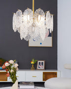 Clérachic pendant with layered clear glass hanging in front of a dark grey wall, flowers and books on the white table below.