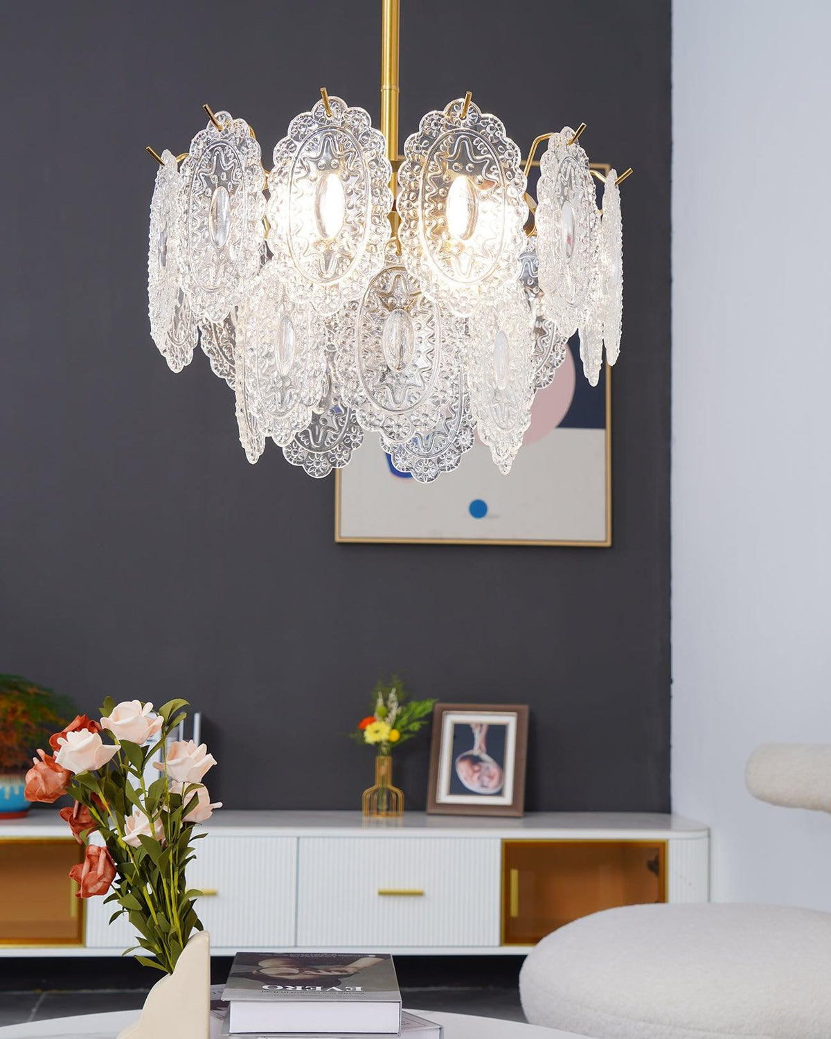 Clérachic pendant with layered clear glass hanging in front of a dark grey wall, flowers and books on the white table below.