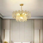 Lit Clérachic pendant centred in a bedroom with tall beige wall panels, above the top of a cream headboard.