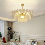 Clérachic glass pendant lit in a calm lounge, with a black floor lamp, a framed print and bright cushions below.