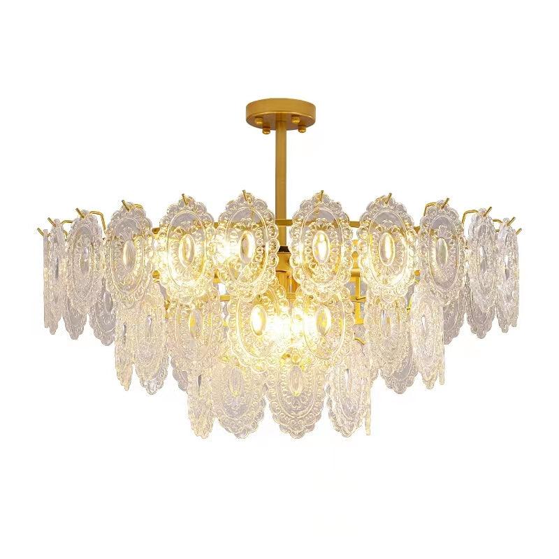 Clérachic gold pendant with layered clear glass panels, lit warm and shown on a plain white backdrop.