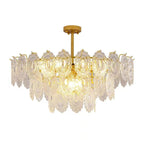Clérachic gold pendant with layered clear glass panels, lit warm and shown on a plain white backdrop.
