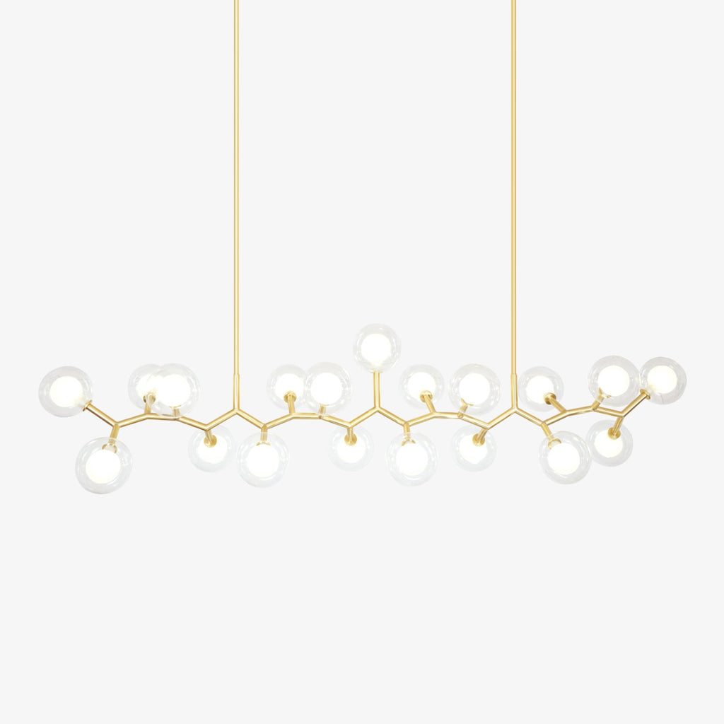 Gold branched chandelier with clear glass globes around white inner shades, hung from two rods on a plain white backdrop from Clérachic.