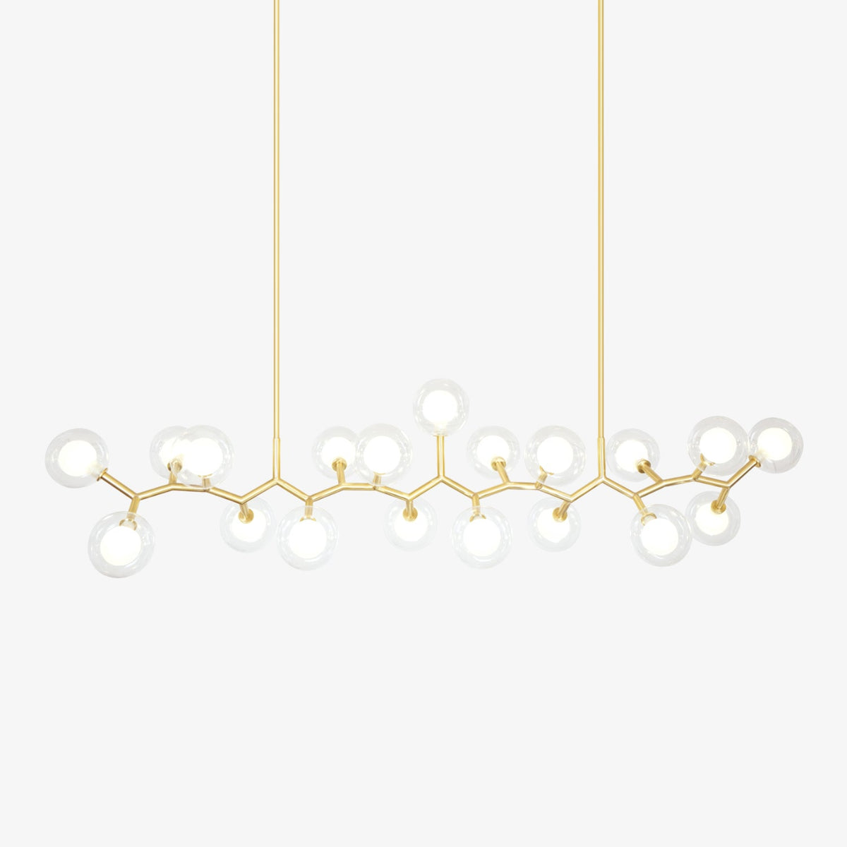 Gold branched chandelier with clear glass globes around white inner shades, hung from two rods on a plain white backdrop from Clérachic.