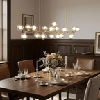 Lit Clérachic globe chandelier hung over a dark wood dining table set with glassware and flowers, with wood panelling behind.