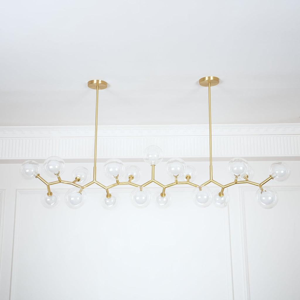 Wide view of the unlit Clérachic chandelier, its clear glass globes spread along gold branches under two slim hanging rods.