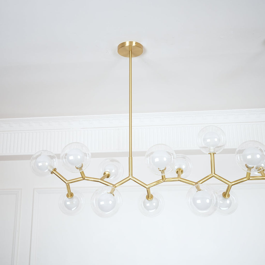 Close view of the gold branches and clear glass globes on one side of this Clérachic chandelier, hung from a single central rod.