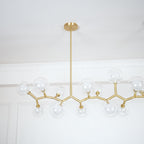 Close view of the gold branches and clear glass globes on one side of this Clérachic chandelier, hung from a single central rod.