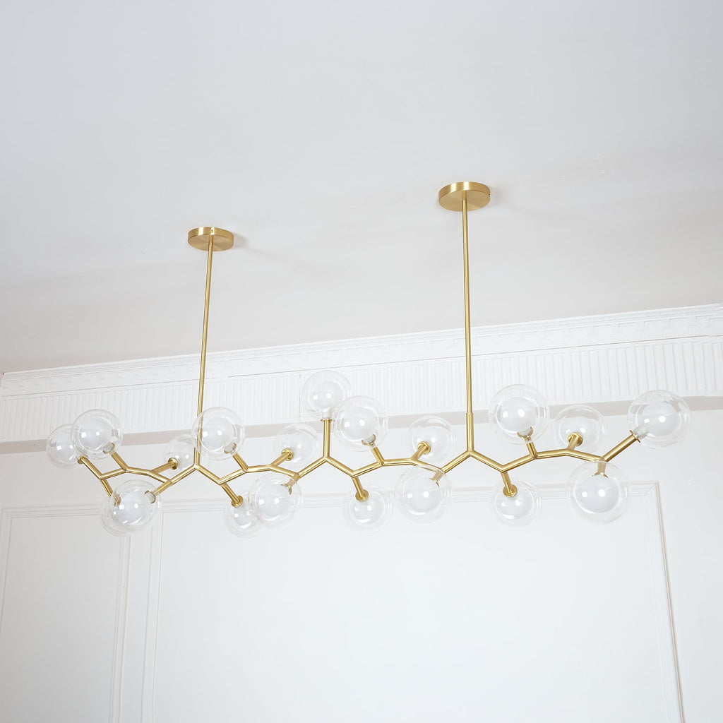 Angled view of the unlit Clérachic chandelier, its clear globes and gold branches hung from two rods of different lengths.