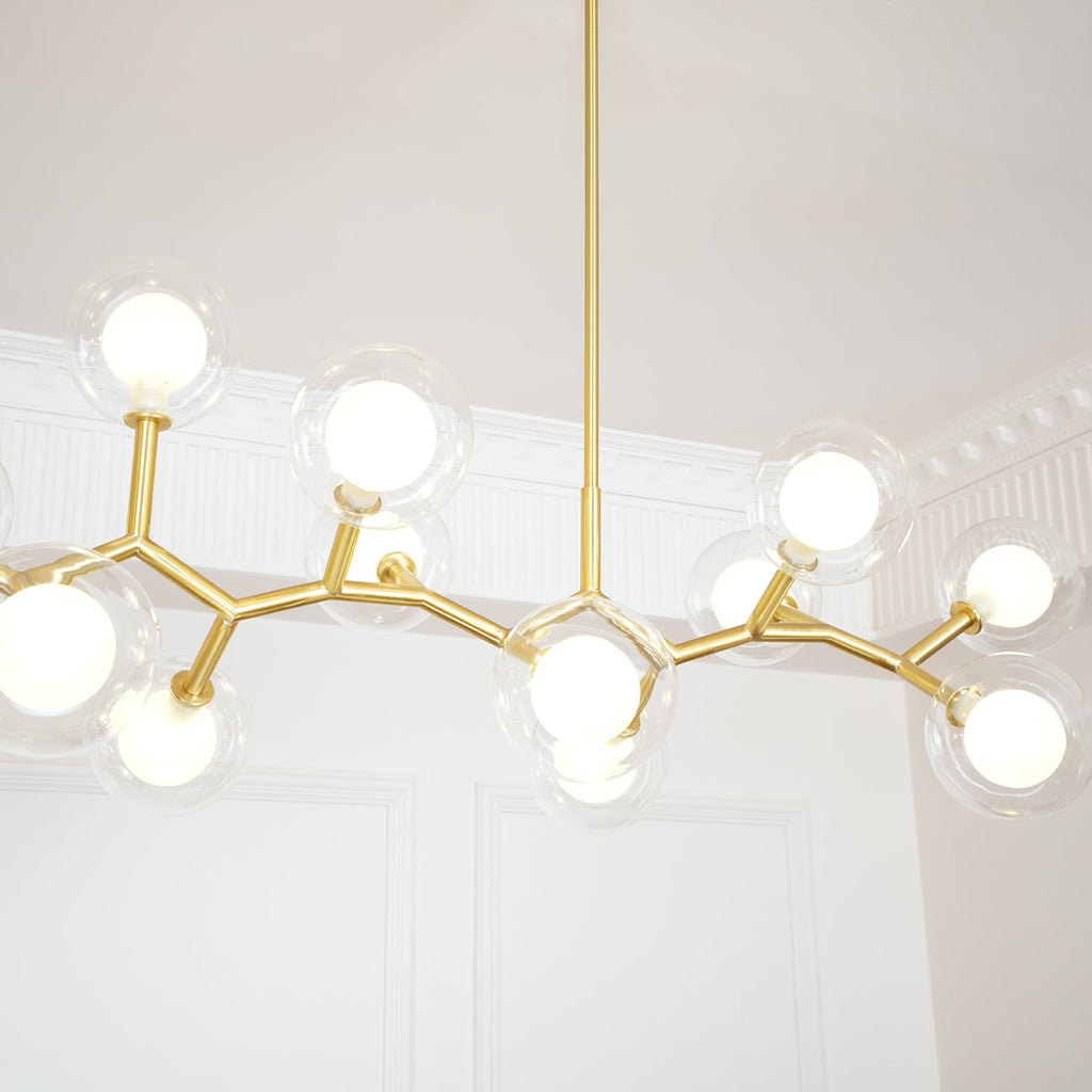 Close view of lit white inner globes inside clear outer glass on the gold branches of this Clérachic chandelier.