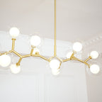 Close view of lit white inner globes inside clear outer glass on the gold branches of this Clérachic chandelier.