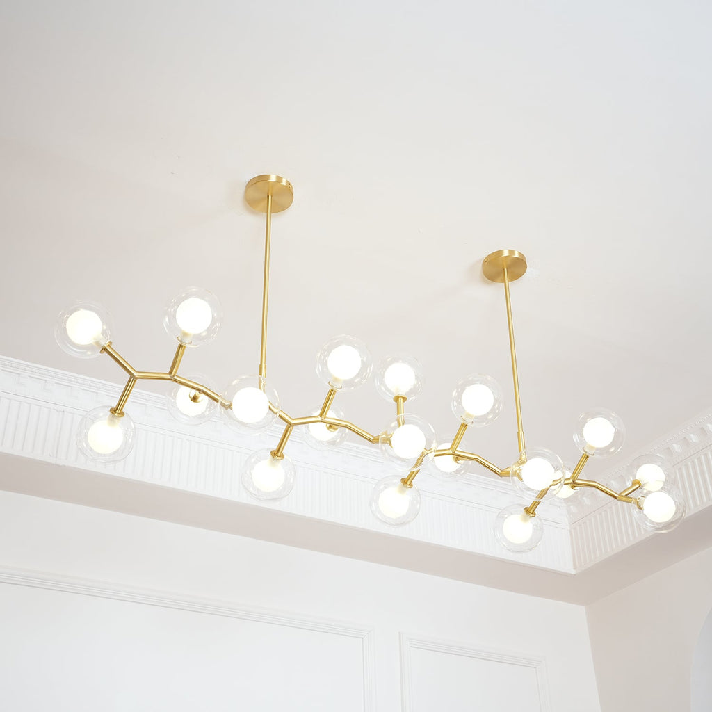 Lit Clérachic chandelier hung from two gold rods, with glowing globes spread along zigzag gold branches under a moulded ceiling.