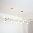 Clérachic chandelier lit with its globes on gold branches, seen at an angle beside an arched doorway and white ceiling moulding.