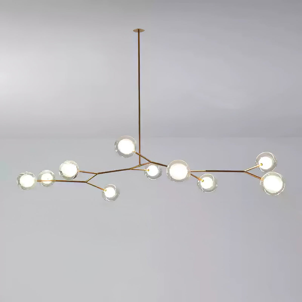 Medium Clérachic gold-branch chandelier with around ten lit glass globes, hung from a single long rod on a grey backdrop.