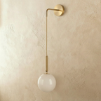 Clérachic gold globe wall sconce shown straight on, opal glass globe suspended below a jointed brass arm.