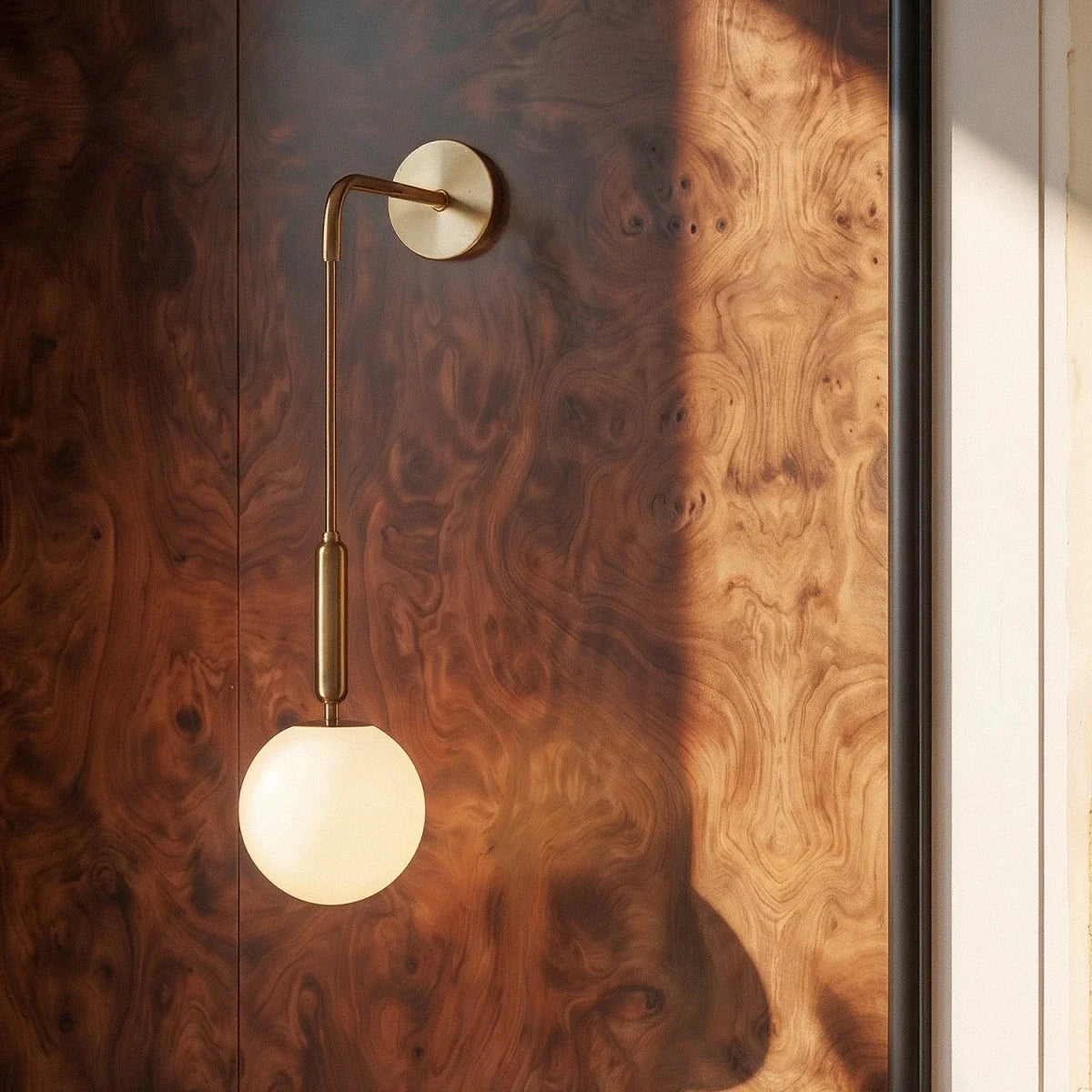 Detail of the Clérachic gold globe sconce's brass arm and connector against richly grained burl wood paneling.