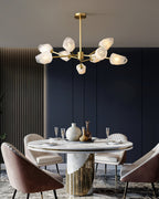 This Clérachic chandelier lit above a round marble dining table with blush velvet chairs against a navy panelled wall.