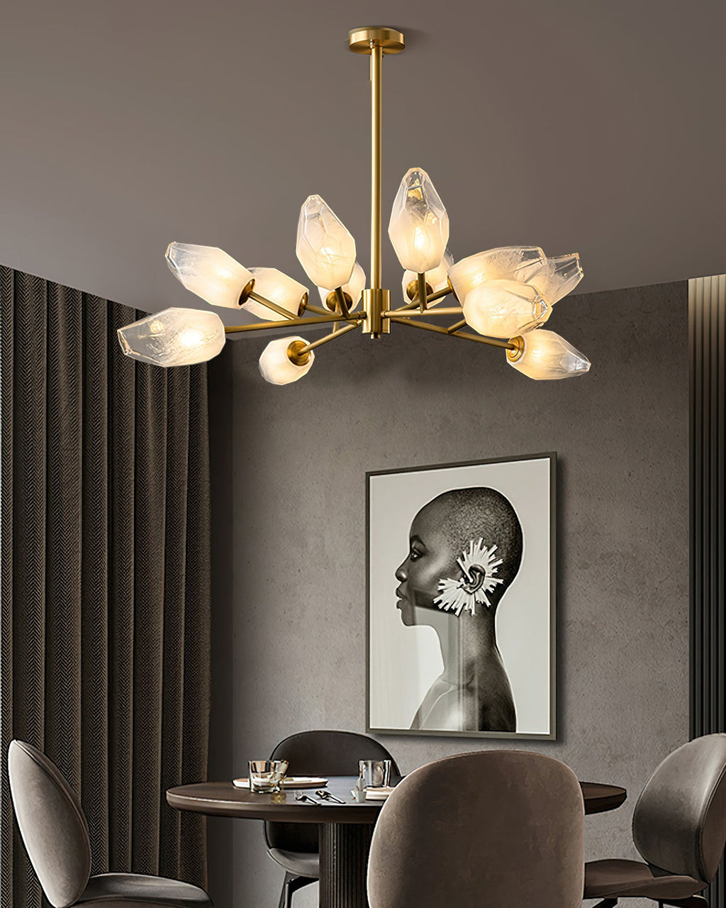 A Clérachic chandelier with a long brass rod above a dark dining table, with a monochrome portrait on the grey wall.