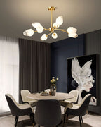 Compact Clérachic chandelier with frosted glass shades beside tall drapes, over a round dining table with dark chairs.