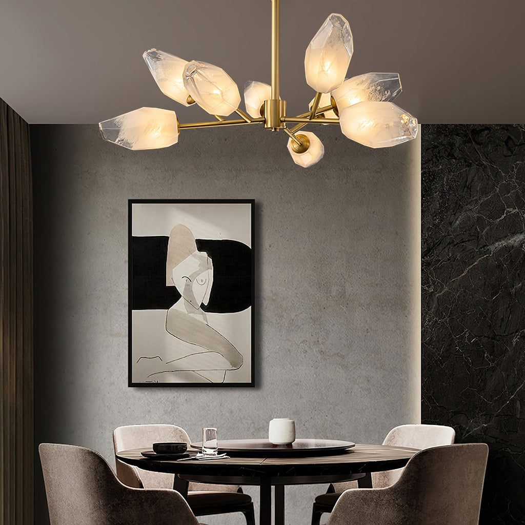 Close, low angle on a Clérachic chandelier lit above a round dining table, with a framed black and white drawing behind.