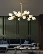 A Clérachic chandelier with frosted glass shades above a navy sofa and marble tables, set against olive-green wall panels.
