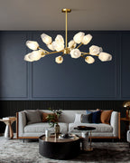 This Clérachic chandelier with many frosted shades hung in front of a dark blue wall above a grey two-seat sofa.