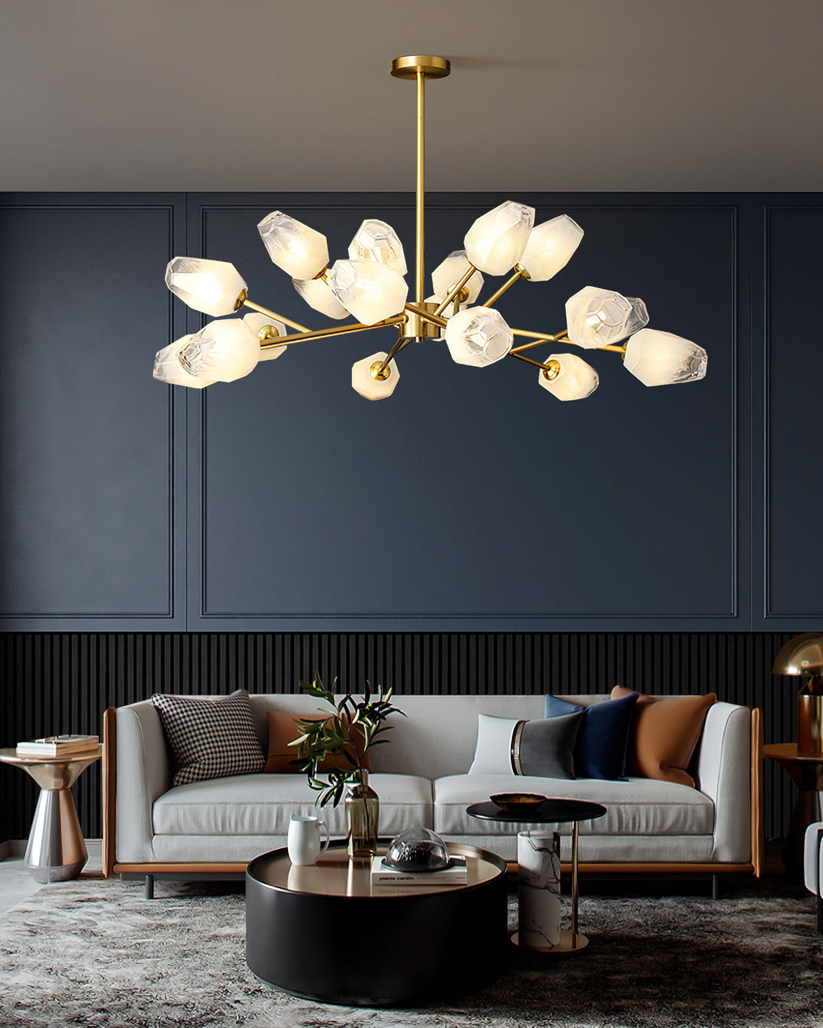 This Clérachic chandelier with many frosted shades hung in front of a dark blue wall above a grey two-seat sofa.