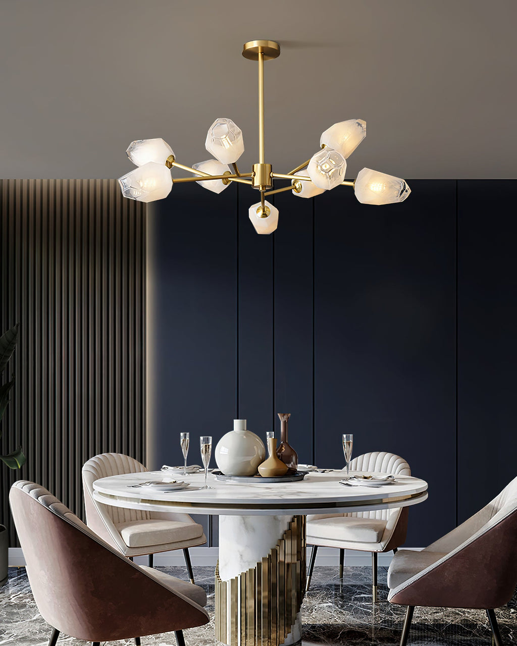 This Clérachic chandelier lit above a marble-based dining table with pink chairs and a dark navy wall behind.