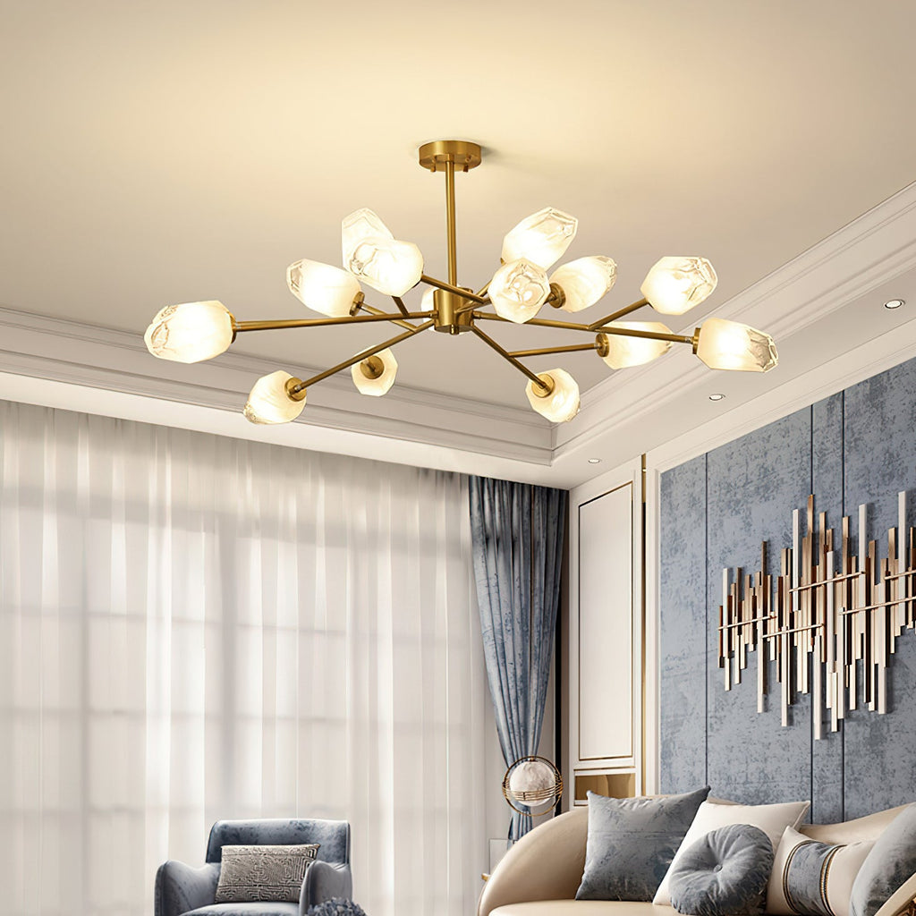 A Clérachic chandelier with brass arms and glass shades in a bright living room with a moulded ceiling and sheer curtains.