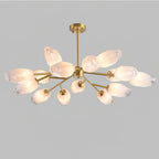 Gold chandelier with frosted glass shades in a soft glow, this Clérachic ceiling light on a plain light grey backdrop.