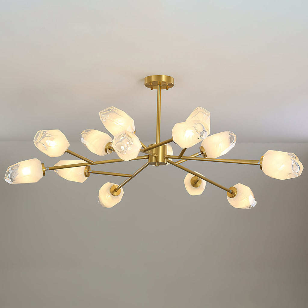 This Clérachic chandelier with a short brass stem and many shades, lit on a pale grey backdrop.