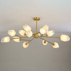 This Clérachic chandelier with a short brass stem and many shades, lit on a pale grey backdrop.