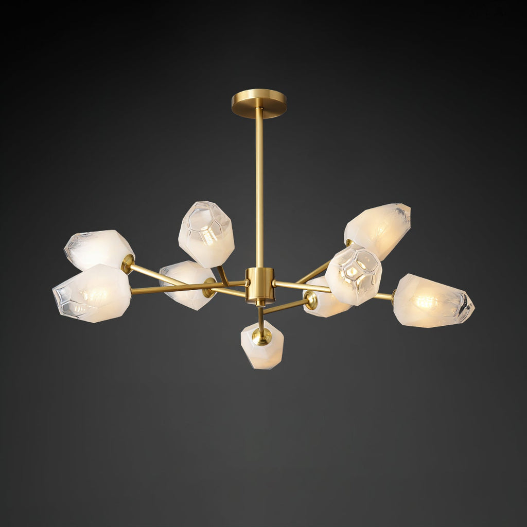 Unlit frosted white glass shades on the brass arms of this Clérachic chandelier, on a dark grey studio background.
