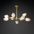 Unlit frosted white glass shades on the brass arms of this Clérachic chandelier, on a dark grey studio background.