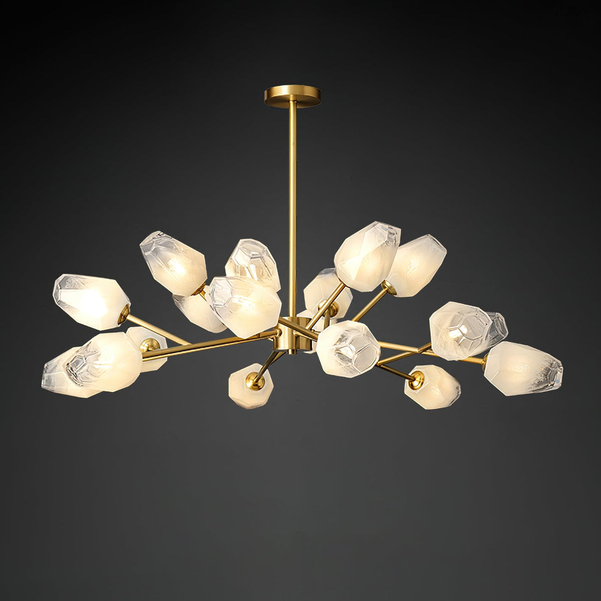 A Clérachic chandelier lit against a dark studio backdrop, with a brass rod and a wide spread of frosted shades.