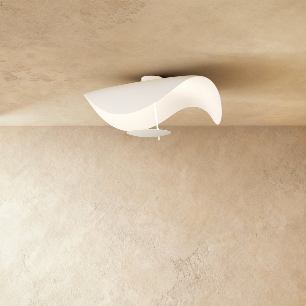 A curved, sail-shaped Clérachic ceiling light in matte white mounts flush against a plastered ceiling.