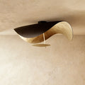 This Clérachic ceiling light shows its black top shell opening to a warm gold-leaf underside.
