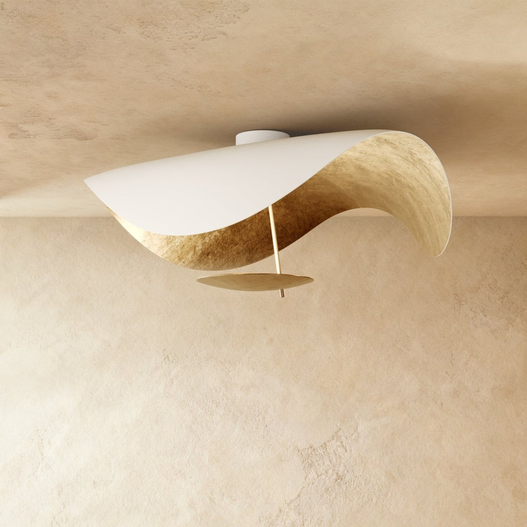 A Clérachic ceiling light in white with a gold-leaf inner curve catches the light from below.