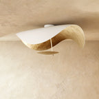 A Clérachic ceiling light in white with a gold-leaf inner curve catches the light from below.