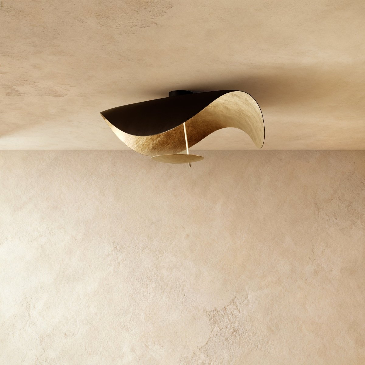 Seen at an angle, this Clérachic ceiling fixture pairs a black outer shell with a gilded gold-leaf interior.