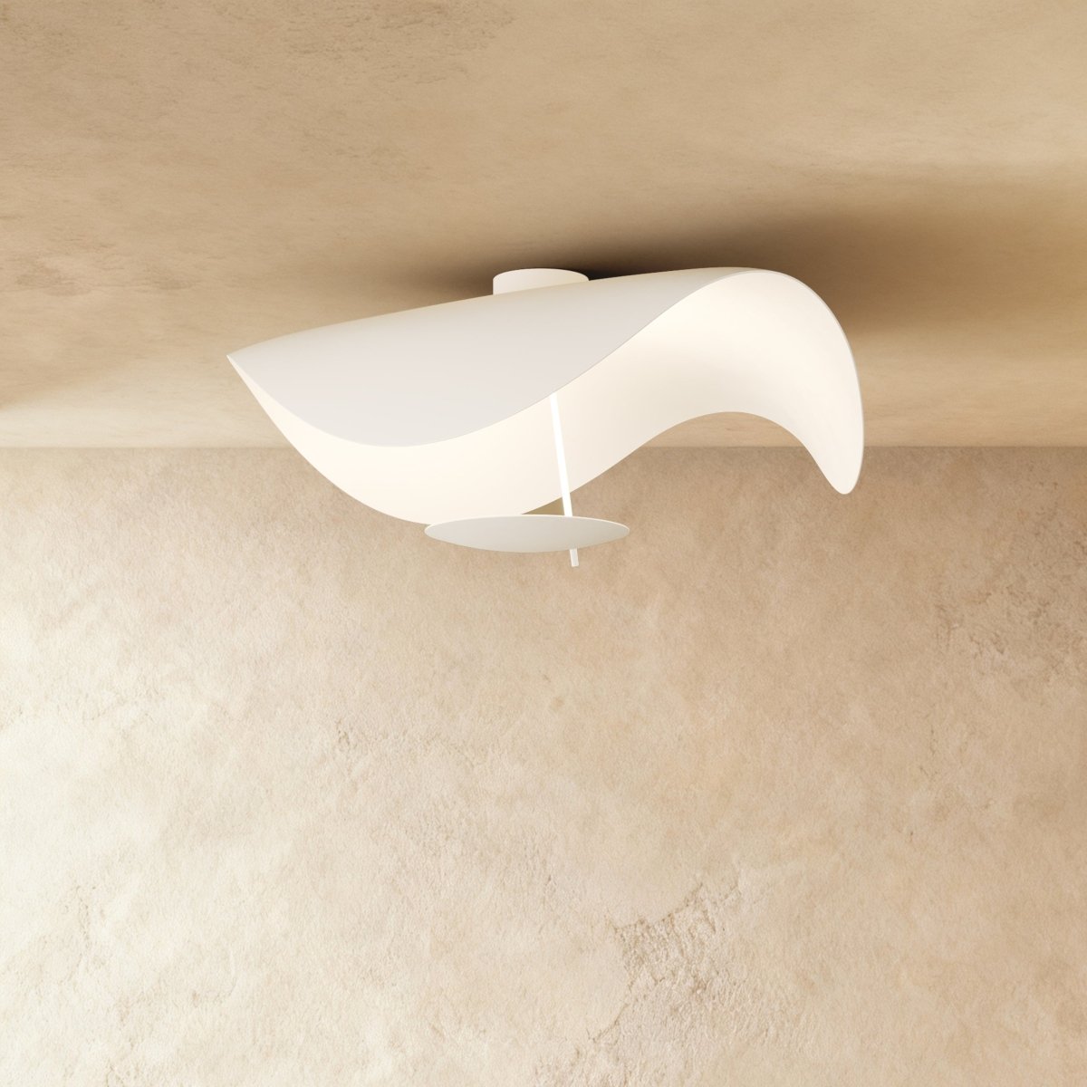 This Clérachic ceiling light in matte white curves like a wave, its round diffuser plate hanging just below the shade.