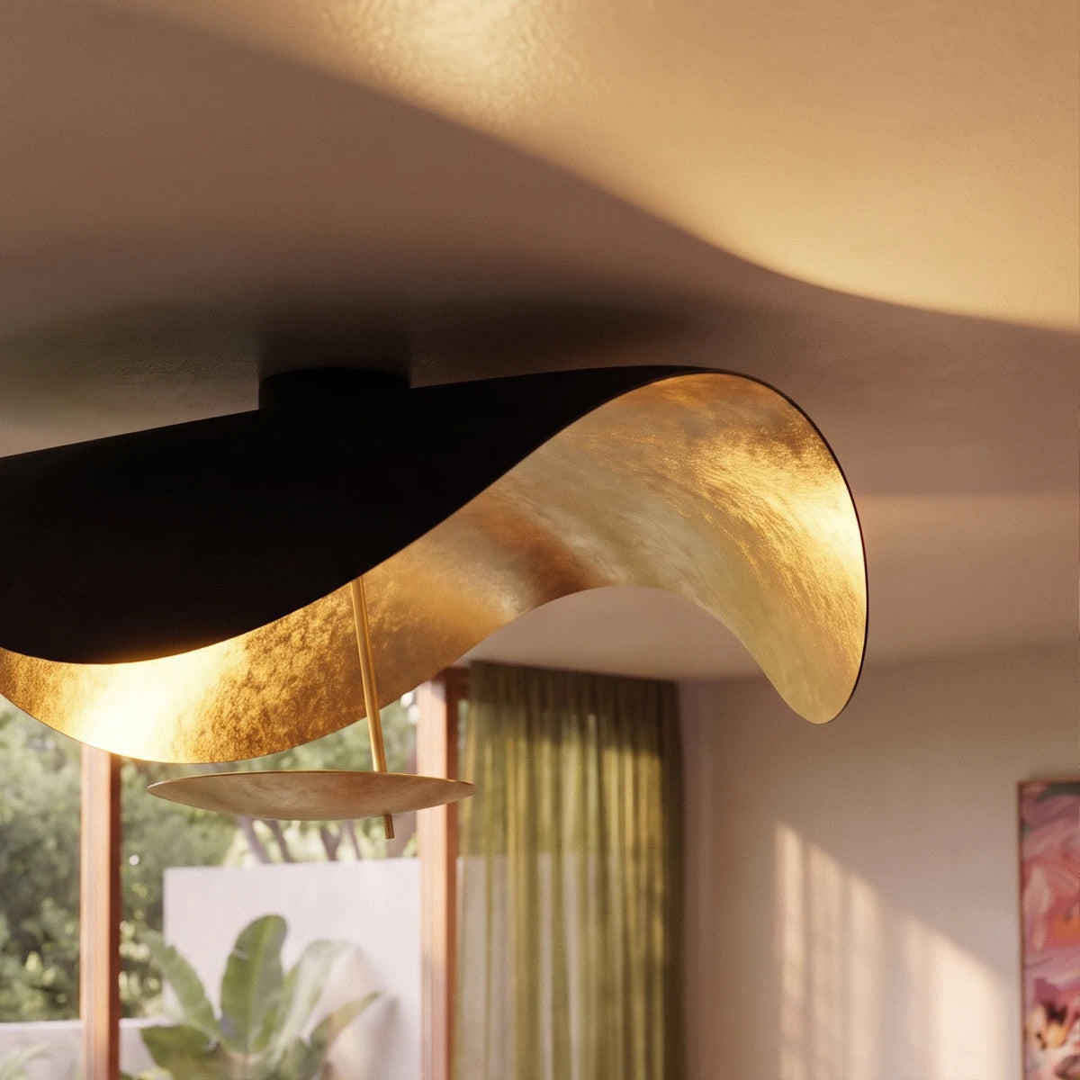 Backlit by a sunlit window, the Clérachic ceiling light's black shell and gold-leaf curve stand out in close detail.