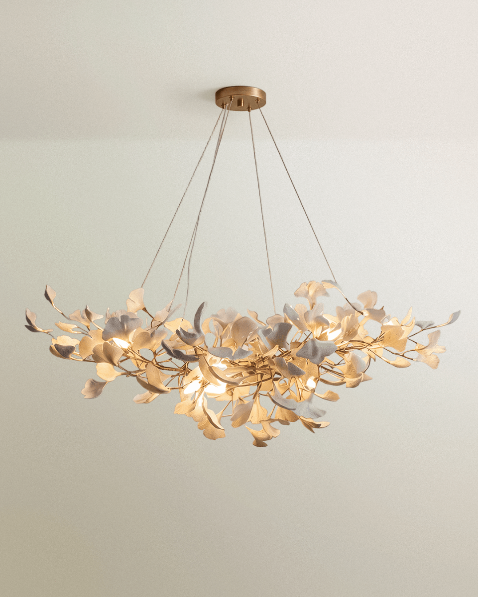 Clérachic round gold chandelier of pale leaf shapes on branching stems, hung from a brass ceiling plate on four cables.